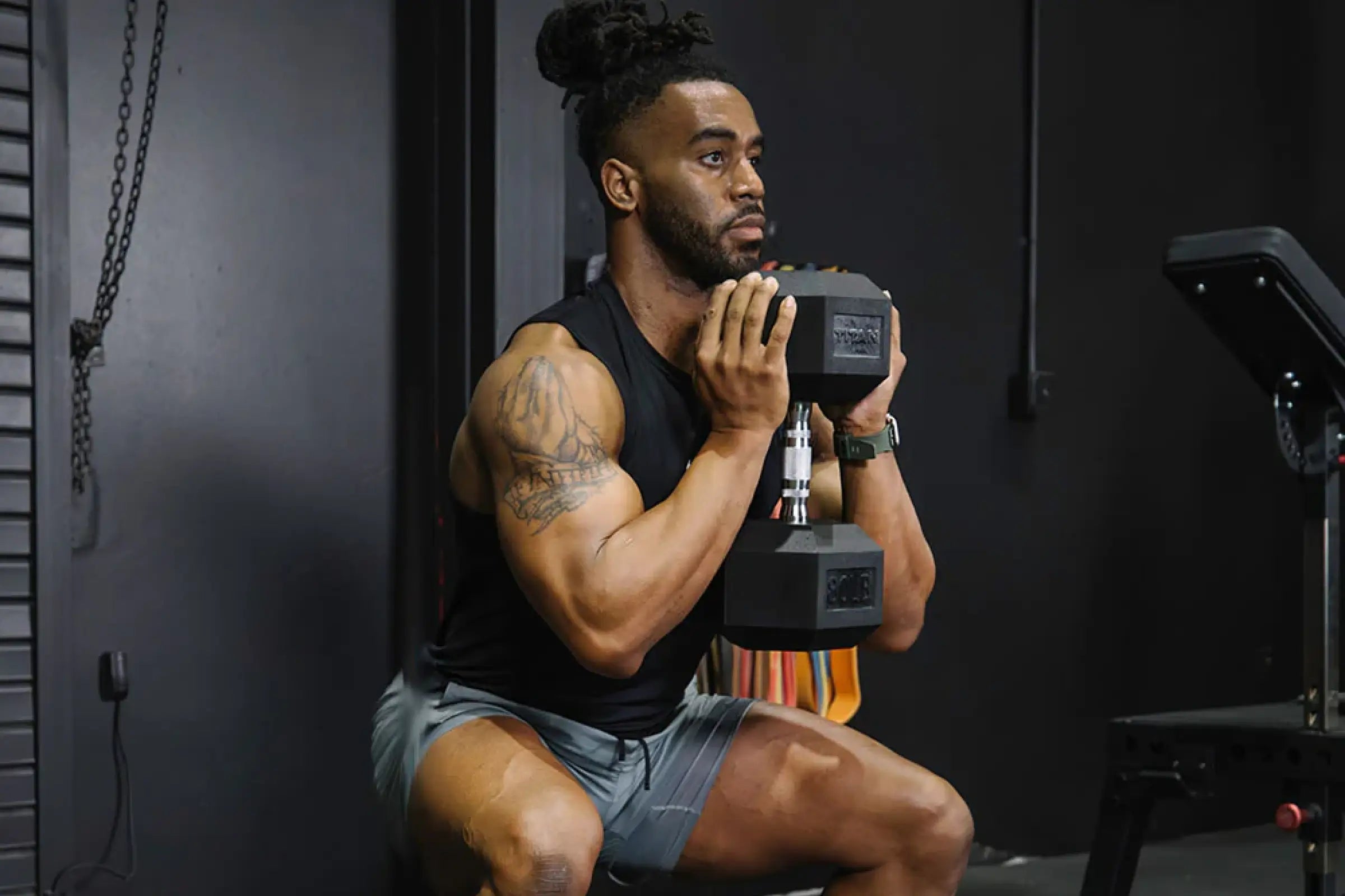 Man performing a goblet squat with a getfitnesstrendy.com rubber hex dumbbell in a home gym.